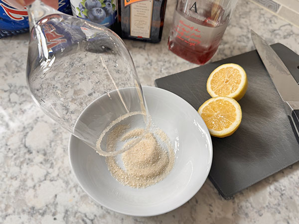 Dipping a wine glass in sugar to create sugar rim.