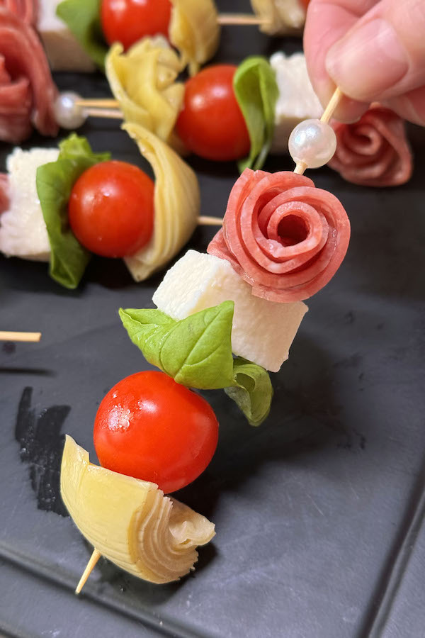 Tomato mozzarella basil skewer with salami rose and marinated artichoke.