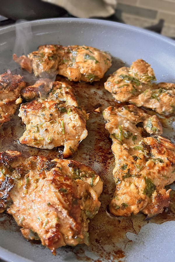 Fully cooked golden brown Mexican style chicken thighs in a skillet.