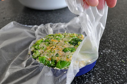 Shaping broccoli patty using a lid from a mayo jar as a help.