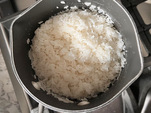Cooke sushi rice in a saucepan.