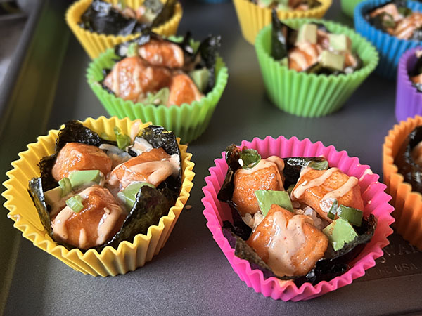 Baked salmon sushi bites topped with avocado and green onions.